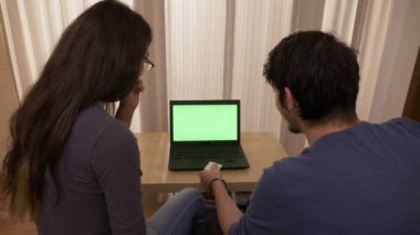 Genç mutlu çifte rezervasyon online tatil yeşil ekran ile bir dizüstü bilgisayar kullanarak