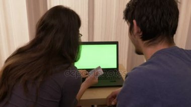 Sevgi genç çift yeşil ekran ile bir dizüstü bilgisayar kullanarak evden alışveriş online
