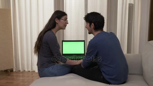 Attraktiv ung kvinna med glasögon som försöker övertyga sin pojkvän att göra online shopping — Stockvideo