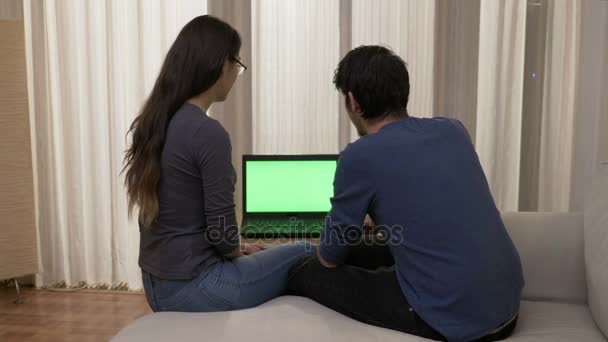 Fidanzato che mostra prodotti sul sito internet alla sua ragazza nel soggiorno utilizzando un computer portatile con schermo verde — Video Stock