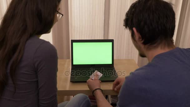 Jong stel ervaren problemen met credit card terwijl het doen van online winkelen met behulp van een laptop met groen scherm — Stockvideo