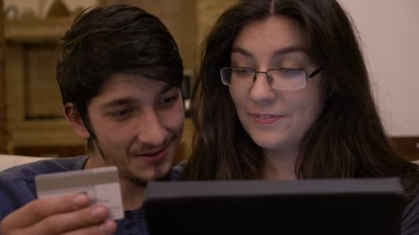 Cariñoso besos joven pareja en casa usando tableta pc introducción de información de tarjeta de crédito para comprar en línea — Vídeos de Stock