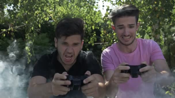 Conceito de intensa competição feroz entre dois jovens jogadores com joystick viciados em videogames de console cobertos de fumaça em câmera lenta — Vídeo de Stock