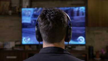 Dijital monitör Tv önünde oyun evde büyük kulaklıklar rahatlatıcı ile büyüledi genç adam oyuncu