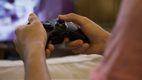 Closeup of young man hands using joystick playing video games on large TV screen at home — Stock Video