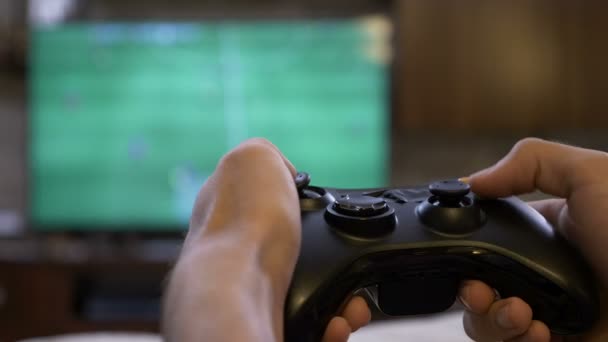 Zbliżenie koncentruje się mężczyzna ręce trzymając gamepad, zabawy, gry w piłkę nożną gra wideo na konsolę — Wideo stockowe