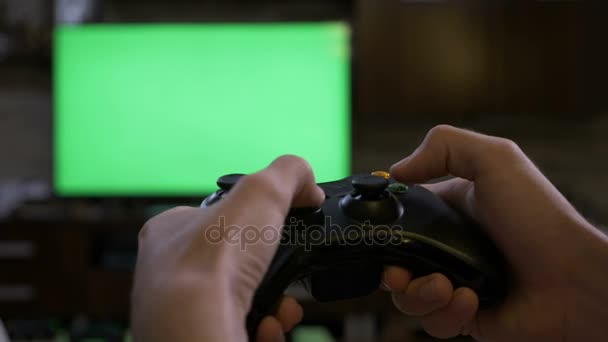 Primer plano de las manos masculinas jóvenes jugando en la consola de videojuegos que controla el joystick en la pantalla de televisión de pantalla verde croma key — Vídeos de Stock