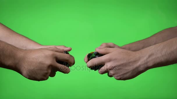 Два нервных молодых видеогеймера с беспроводными контроллерами лицом друг к другу в матче на зеленом фоне экрана — стоковое видео