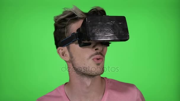 Teenage man experiencing for the first time an amazing experience of virtual reality wearing VR headset gadget on green screen — Stock Video