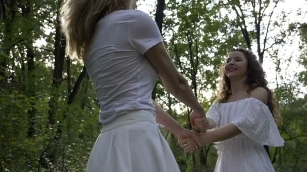 İki güzel kız beyaz melek elbiseler giymiş yeşil ormanda dans — Stok video