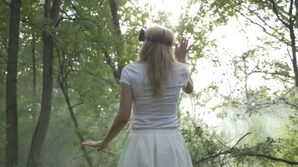 Junge Frau mit Kopfhörer im Wald erlebt erweiterte virtuelle Realität — Stockvideo