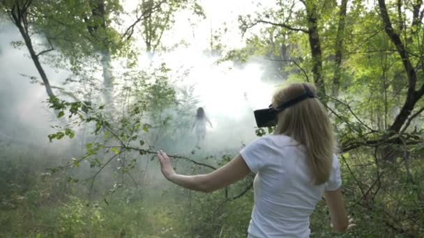 Mulher com óculos de realidade virtual seguindo vr fantasma menina em fumaça na floresta — Vídeo de Stock