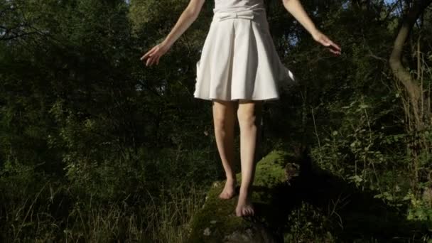 Pés de mulher jovem andando em um tronco de árvore coberto com musgo de urso na natureza — Vídeo de Stock