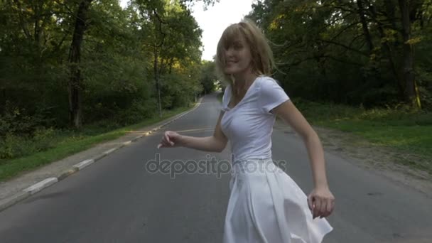 Hermosa rubia atractiva mujer corriendo por un camino forestal y sonriendo — Vídeos de Stock