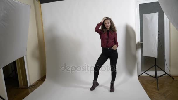 Beautiful model smiling and striking a pose for a young photographer with dark hair in a professional studio in slow motion — Stock Video