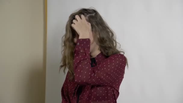 Mooie slanke jonge blonde model vrouw opvallend een pose op een foto's shoot glimlachend en gooien van krullend haar op een witte achtergrond in slow motion — Stockvideo