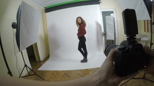 Chica alta rubia vestida de oficina haciéndose pasar por una modelo de moda durante una sesión de fotos profesional con un pov de cámara digital en un estudio con fondo blanco — Vídeo de stock