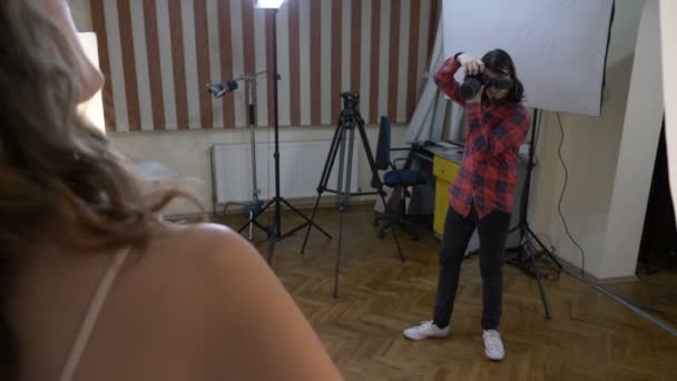 Tizenéves diák fénykép fényképezés barátnője egy professzionális kamerát egy rögtönzött stúdióban otthon a nappaliban — Stock videók