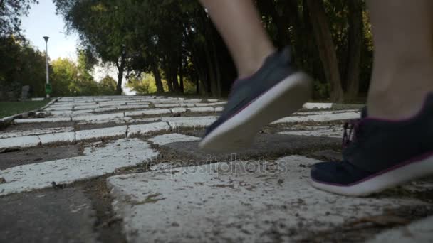 Aantrekkelijke mager meisje met getinte beenspieren joggen op een witte alley park de trap in slow motion — Stockvideo