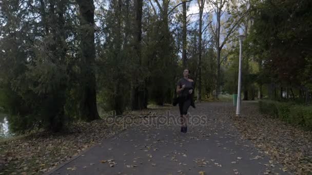 Attraktiva manager kvinna med tonad kropp kör i parken efter jobbet att rensa hennes sinne och bli av med stress i slow motion — Stockvideo