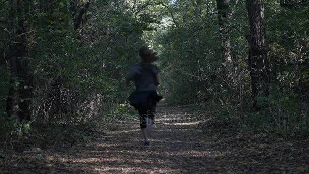 Приваблива молода жінка біжить в природі через тіньовий ліс в спекотний літній день, щоб поліпшити її психічне здоров'я — стокове відео