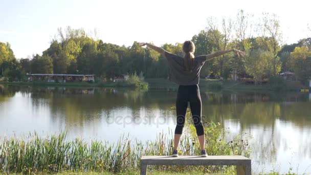 Aantrekkelijke jonge meisje inademen en uitademen doen yoga strekt zich uit in een park op een mooie zomerdag — Stockvideo