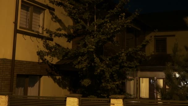Extérieur d'une maison intelligente européenne jaune du quartier résidentiel étant automatiquement éclairée dans chaque pièce — Video