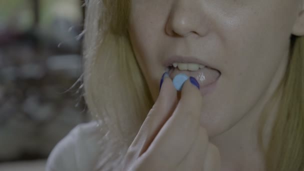 Close up de uma jovem mulher engolindo uma pílula redonda azul e beber um copo de água — Vídeo de Stock