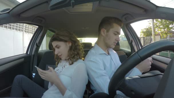 Коханці сидять у своїй машині назад і грають на своїх телефонах у соціальних мережах — стокове відео