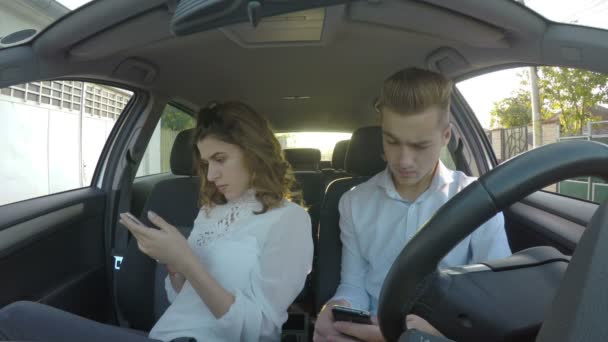 Pareja sentada en el coche y usando teléfonos inteligentes para las redes sociales y sorpréndete — Vídeos de Stock