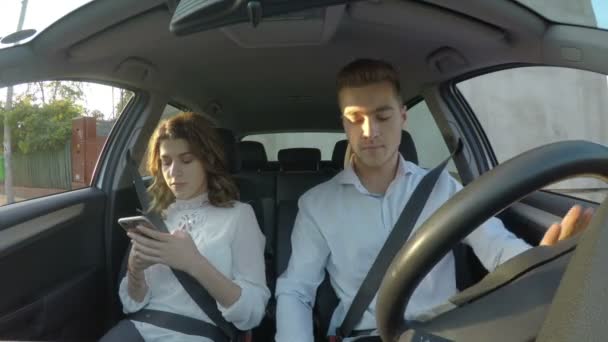 Conductor y novia usan teléfonos inteligentes y mensajes de texto mientras conducen y no prestan atención a la carretera — Vídeos de Stock