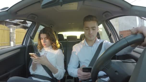 Chauffeur et petite amie dans la voiture ne prêtant pas attention à la route à la fois en utilisant des téléphones intelligents et textos pendant la conduite — Video