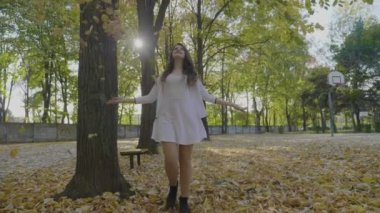 İnce model kız gülümseyerek ve düşen sonbahar arasında iplik Park'ta bir gün zevk özgürlük yavaş zevk bırakır