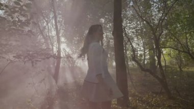 Duman yavaş hareket ile bir sonbahar gününde ormandaki bir photoshoot tadını uzun saçlı genç kız