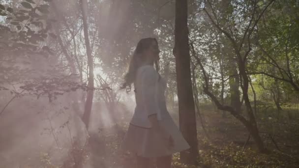 スローモーションで煙で秋の日に森で撮影を楽しんでいる長い髪の 10 代の少女 — ストック動画
