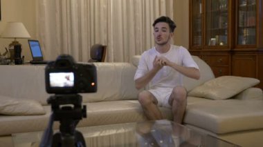 Genç sosyal medya etkileyen yeni bir bölüm video blogunda evde kanepede bir kamera ile çekim