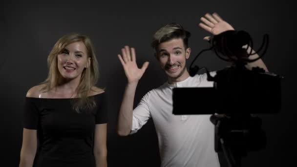 Молода красива жінка і чоловік розмовляють з камерою і представляють свій конкурс відеоблогів у соціальних мережах — стокове відео