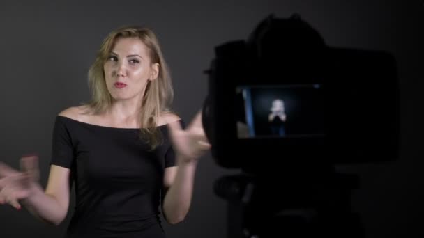 Блондинка привлекательная модель, представляющая и снимающая себя для нового проекта видеоблога в студии — стоковое видео