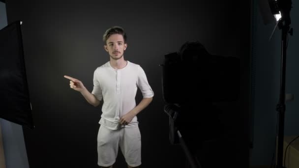 Jongeman tot vaststelling van zijn haar en kleding voordat schieten video achter de schermen voor zijn blog in een professionele studio — Stockvideo