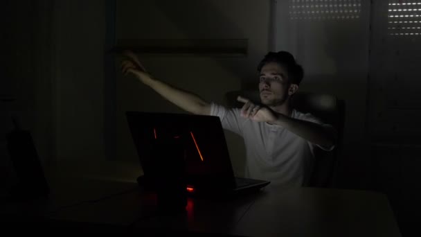 Business man sitting at his desk simulating an interaction with a hologram augmented reality interface screen on his laptop — Stock Video