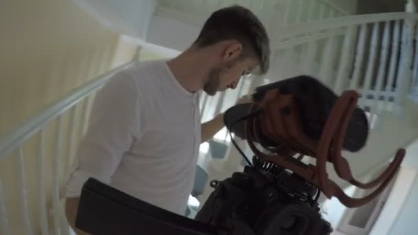 Überrascht junge männliche Vlogger reden und gehen nach oben zu Hause mit einer mobilen professionellen Kamera — Stockvideo