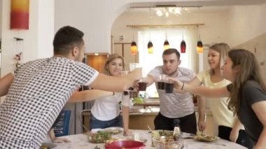 Mutlu arkadaş mutfak toasting, masada oturan ve zevk zaman birlikte evde tezahürat aperatifler ve kola ile parti toplandı