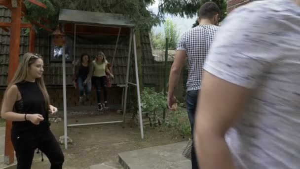 Adolescentes amigos assistindo a churrasqueira lenha enquanto suas namoradas balançando quintal ao ar livre festa pendurado e conceito de lazer fim de semana — Vídeo de Stock