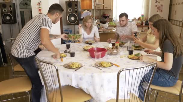 Skupina chlad přátel seděli spolu u stolu a jedli, výživný oběd chatování na domácí příležitostné ďáblů setkání koncept — Stock video