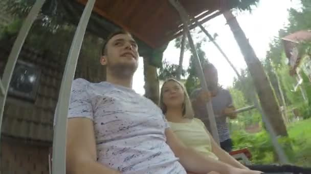 Joyful couple of teenagers having good time in summer vacation on a swing — Stock Video