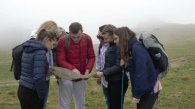 Kağıt harita okuma ve rota Dağı'nda lider sırt çantaları ile genç turist Rota açıklayan profesyonel rehber adam