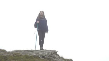 Neşeli dağcı genç kadın uzak manzara seyir dağ tepe üzerinde duran sis çevrili closeup