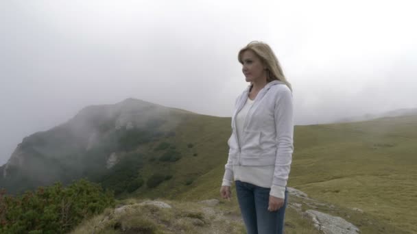 Rilassato giovane donna pacificamente ammirando la natura in piedi sulla cima della montagna godendo la libertà — Video Stock
