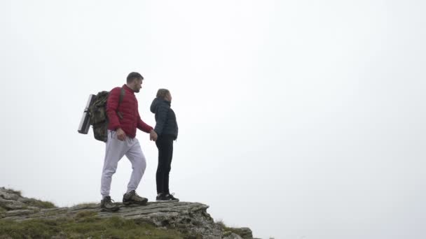 Couple adolescent joyeux célébrant avec les mains levées atteignant le sommet de la montagne profiter de l'aventure — Video