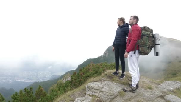 Jovem casal apaixonado caminhadas tomando uma selfie no pico da montanha com paisagem fantástica no fundo — Vídeo de Stock